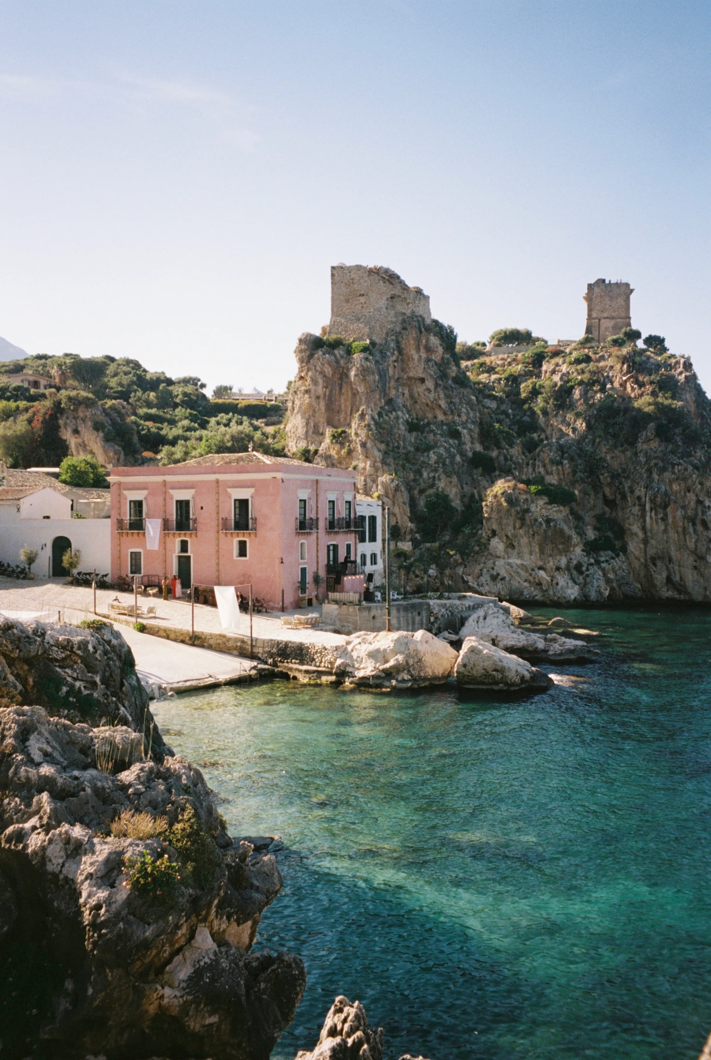 The pink villa and tower above a turquoise cove in Italy