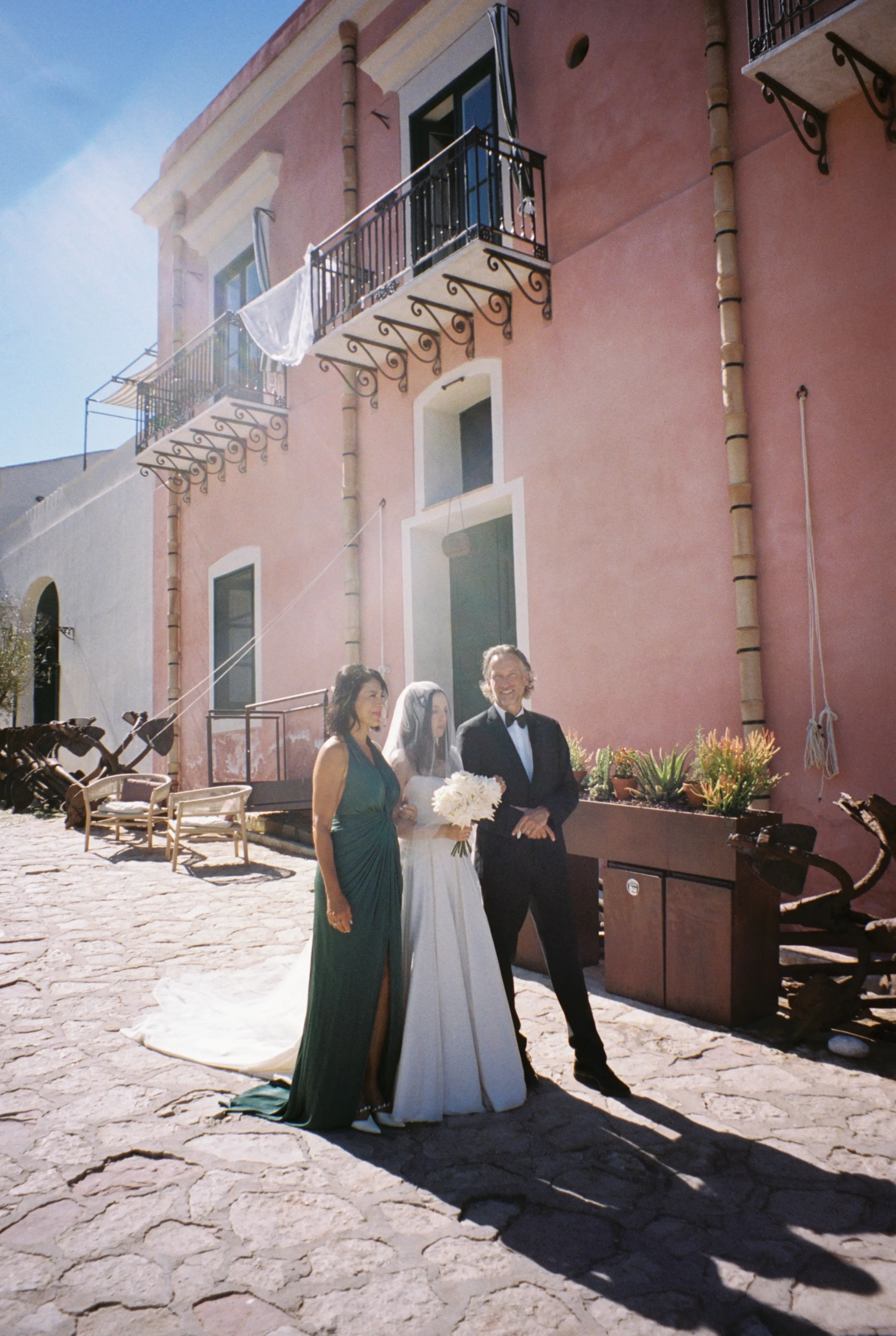 The couple with family in front of the pink facade