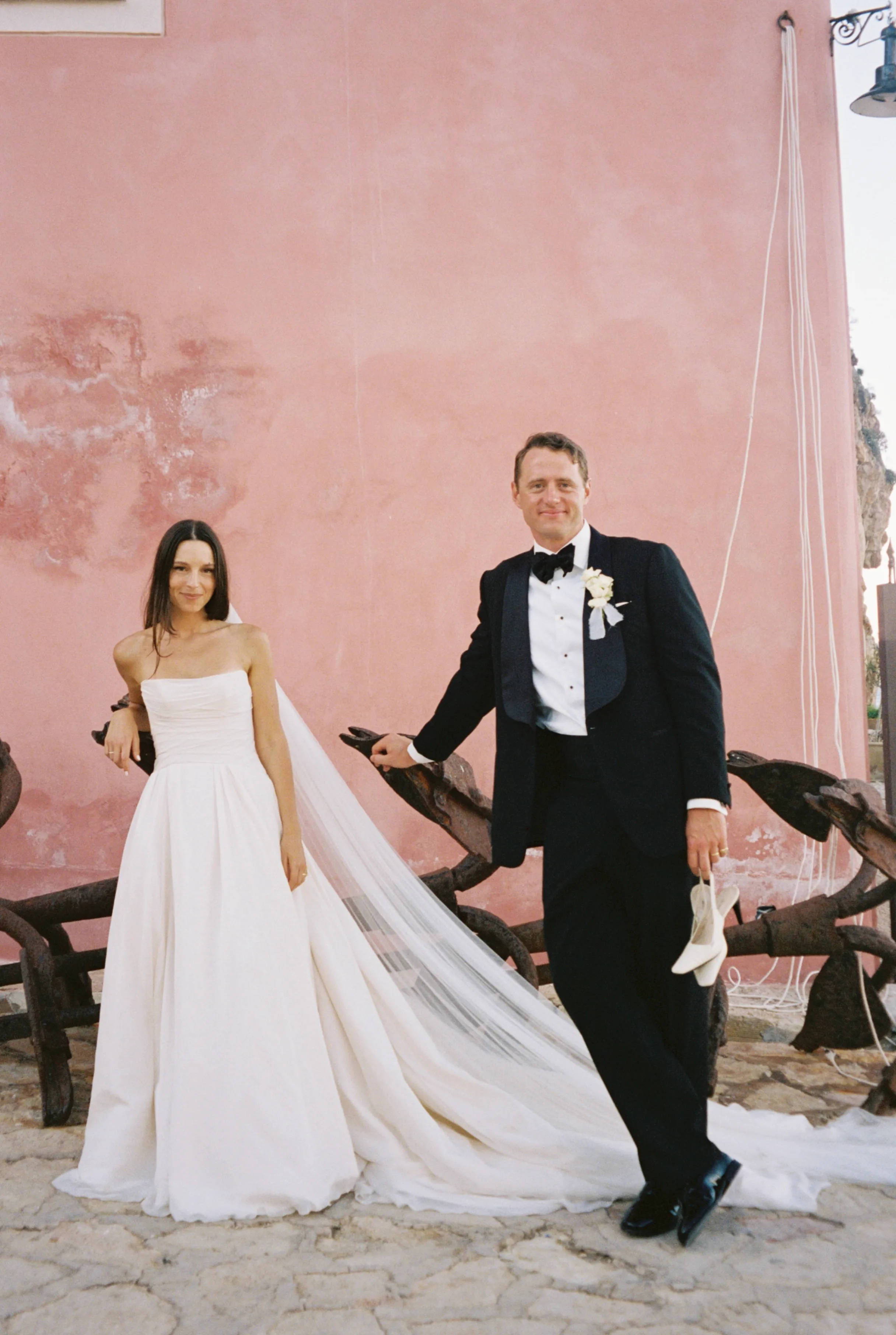 The couple posing against the pink wall